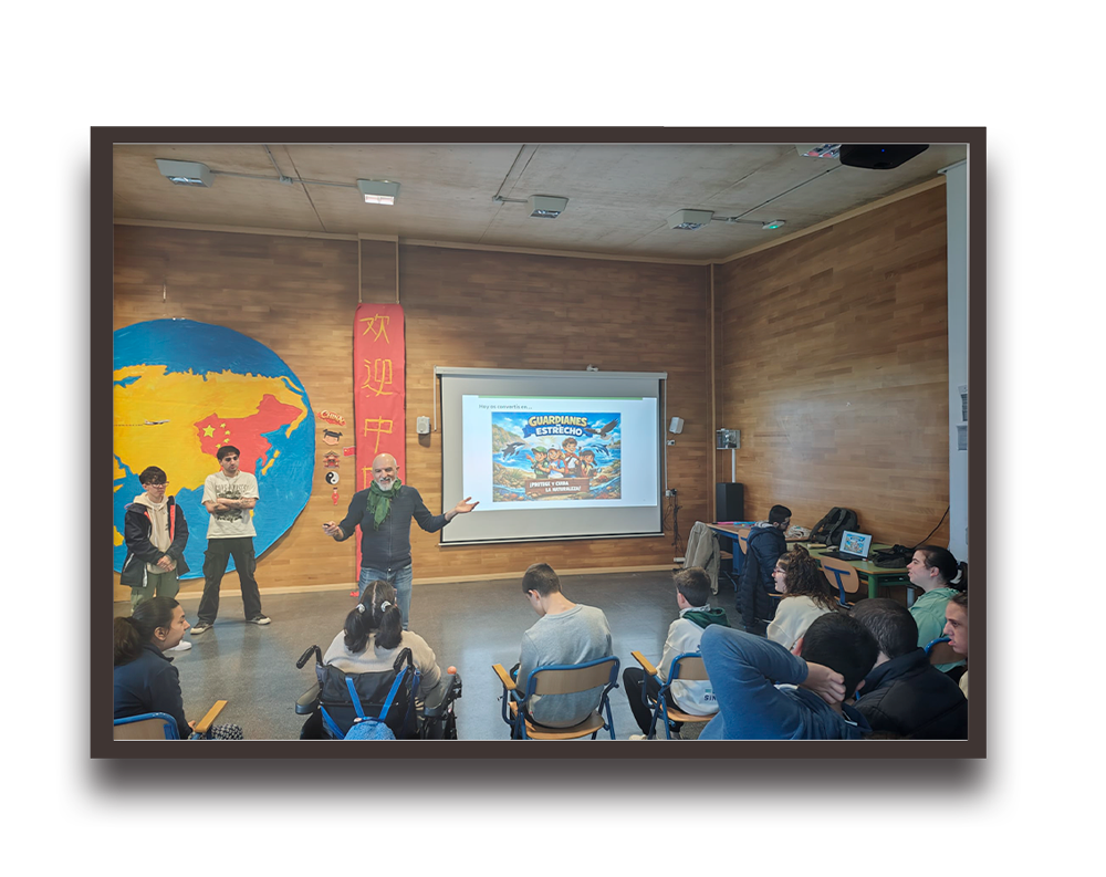Instructor gestures toward a projector screen displaying a colorful poster in a classroom; students sit facing the front, some in wheelchairs.