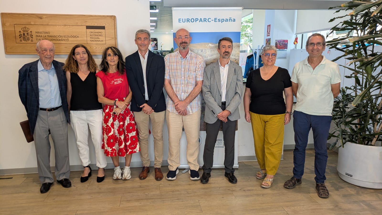 Eight adults in an office posing for a group photo; a EUROPARC-España banner is visible behind them.