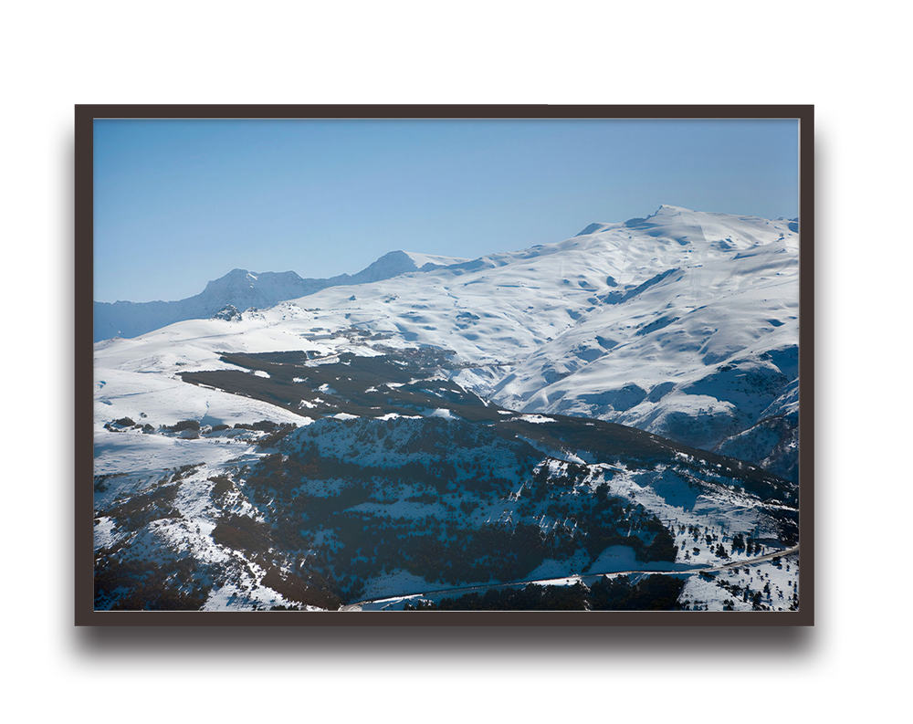 Framed landscape photo of snow-covered mountains under a clear blue sky.